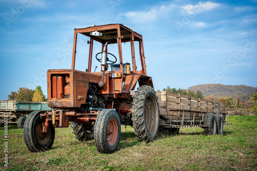 An old rusted tractor with a trailer on farm