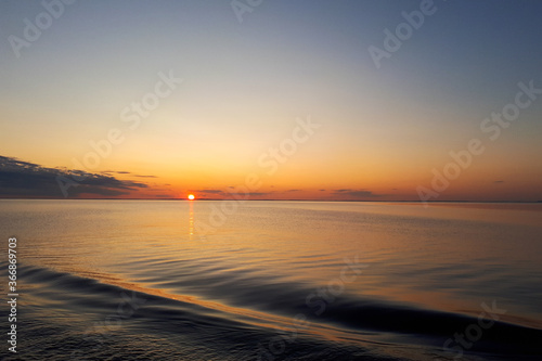 Beautiful sunset over lake on a summer evening. Water waves, recreation concept horizontal photo