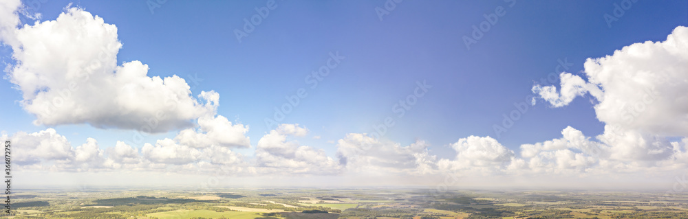 summer rural landscape under blue sky with fluffy clouds. panoramic aerial view of picturesque agricultural fields 