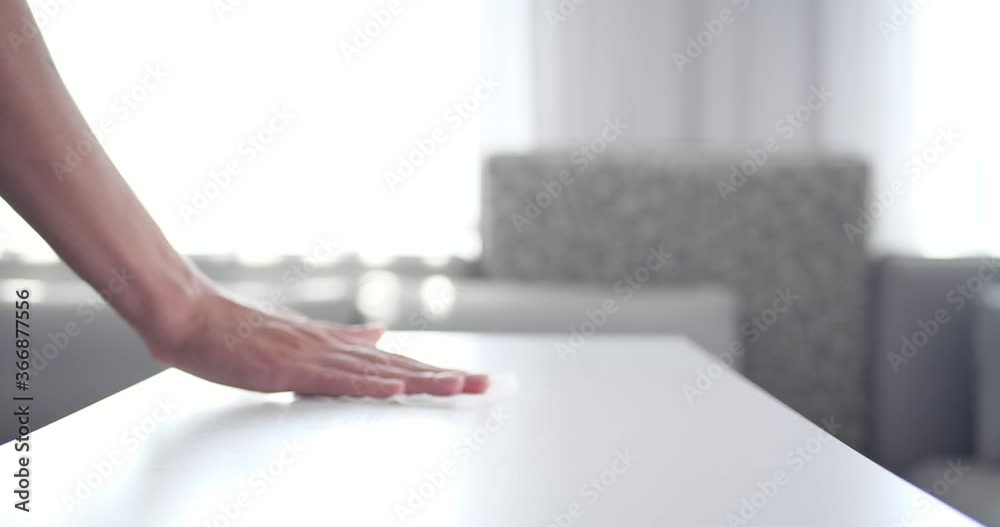 Woman wiping white table with wet tissue, closeup 
