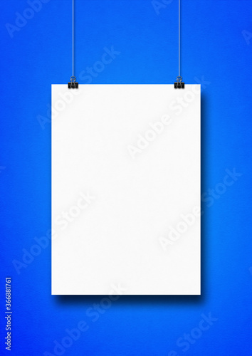 White poster hanging on a blue wall with clips