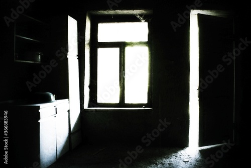 A high grain image of an old abandoned kitchen interior with an open door.