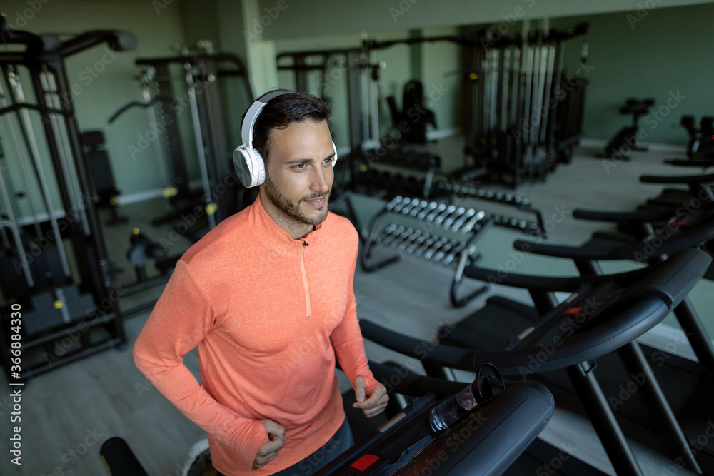 Young athlete warming up on a treadmill during sports training in a gym Young athlete warming up on a treadmill during sports training in a gym