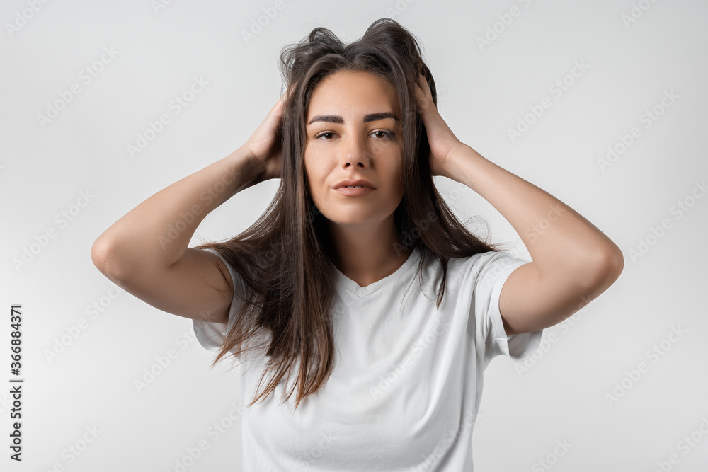 Pretty carefree modern girl with long chestnut hair holding to her head or touching hair. Isolated on white background. Emotions, expressions, hairstyle and people concept. Pretty carefree modern girl with long chestnut hair holding to her head or touching hair. Isolated on white background. Emotions, expressions, hairstyle and people concept.