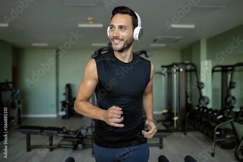 Young happy athlete jogging on running track in health club.