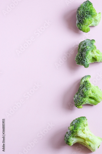 Frozen vegetables such as broccoli cabbage laid out on the right side on a pink background. Copy space. Top view. Vertical orientation. photo