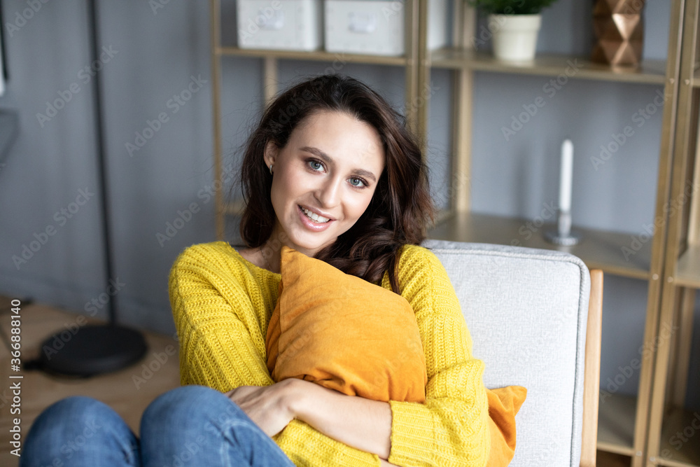 Obraz premium Young woman on the couch with a pillow in her hands at home.^