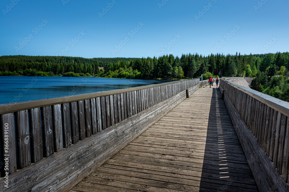people walking on a dam at lake  or reservoir charpal ,Lozere France. a sunny summer day.