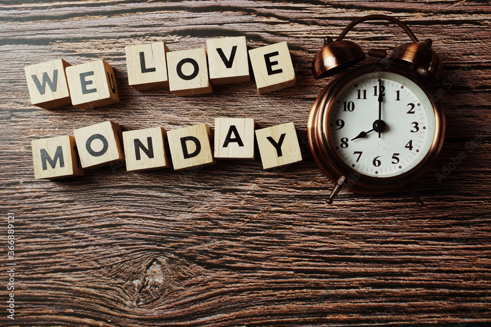 We Love Monday alphabet letter with alarm clock on wooden background