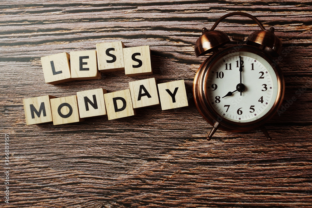 Less Monday alphabet letter with alarm clock on wooden background Less Monday alphabet letter with alarm clock on wooden background
