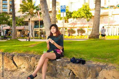 Teenage female tourist eating Hawaiian musubi in Waikiki, Honolulu, Hawaii photo