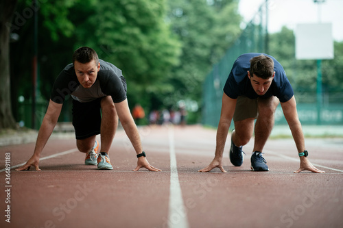 Athlete men in sportswear in start position for running. Close up. 