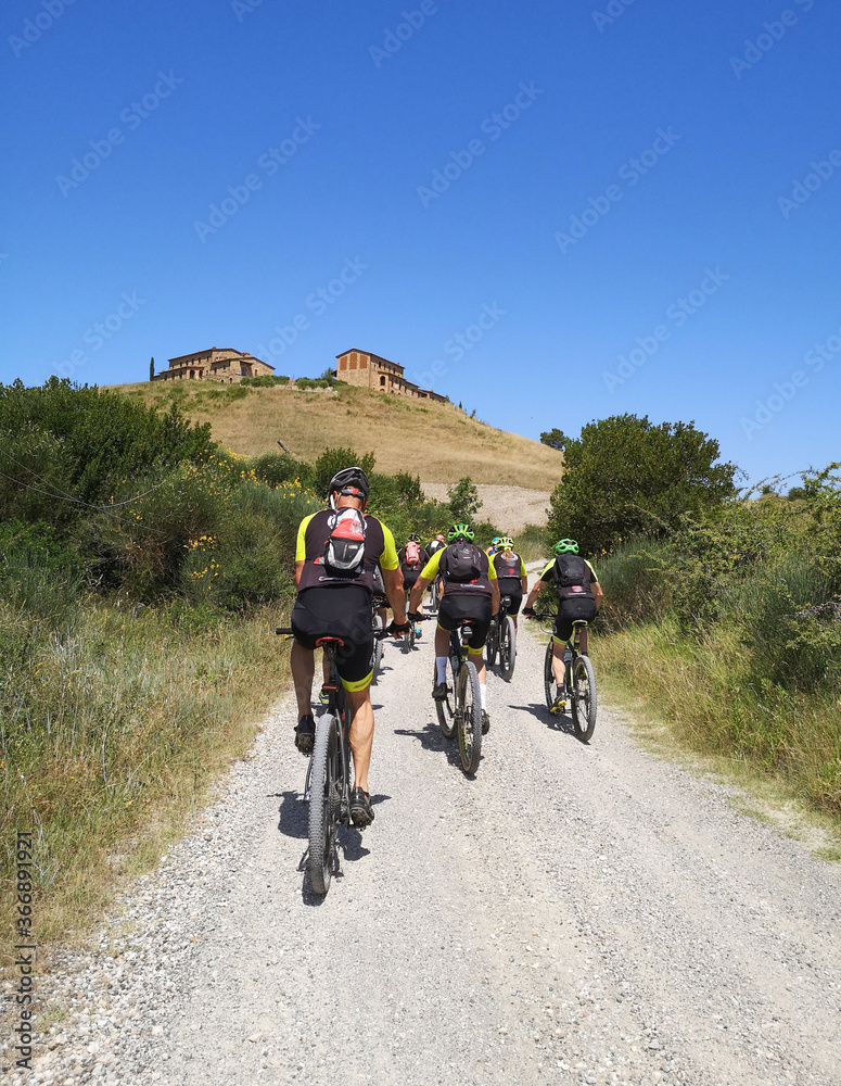 Gruppi di ciclisti viaggiano su una strada panoramica in collina in toscana Gruppi di ciclisti viaggiano su una strada panoramica in collina in toscana