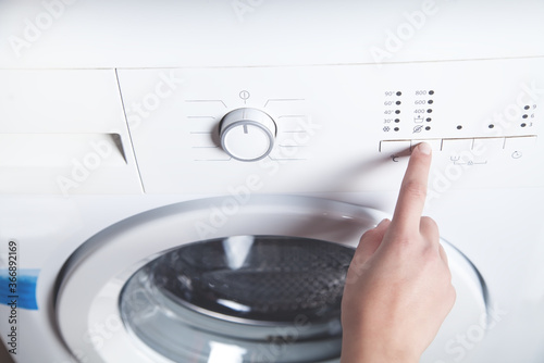 Girl hand pressing button on washing machine.
