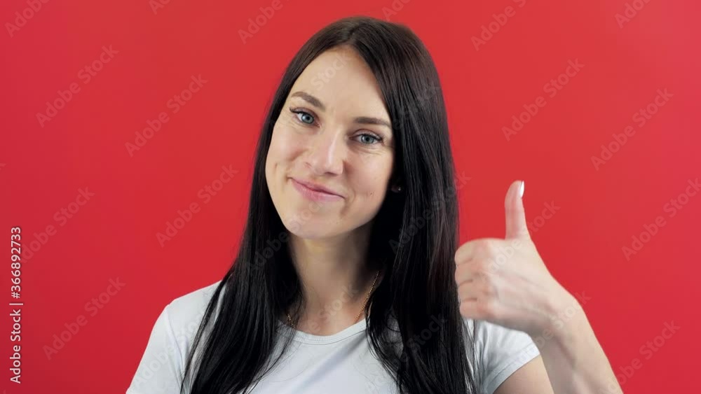Portrait of a happy brunette woman showing thumbs up on red. Woman showing thumb up Portrait of a happy brunette woman showing thumbs up on red. Woman showing thumb up