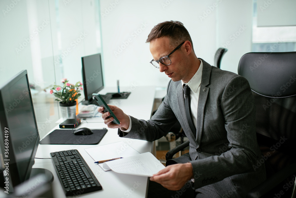 Handsome businessman working in the office. Young man using the phone Handsome businessman working in the office. Young man using the phone