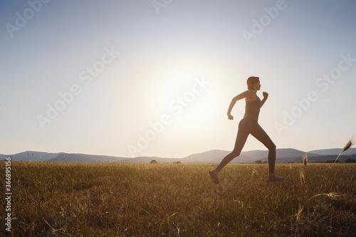 Jogging woman running in summer field at sunset © YURII Seleznov