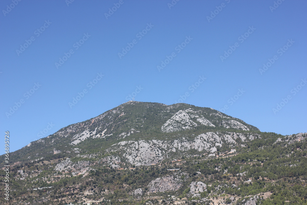 Naklejka premium Alanya, TURKEY - August 10, 2013: Travel to Turkey. Helene Hills. Mountains in the background in the distance. Rocks, wildlife of Turkey. Forest and clear blue sky. Mediterranean Sea.