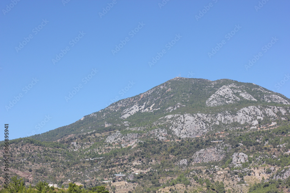 Alanya, TURKEY - August 10, 2013: Travel to Turkey. Helene Hills. Mountains in the background in the distance. Rocks, wildlife of Turkey. Forest and clear blue sky. Mediterranean Sea.