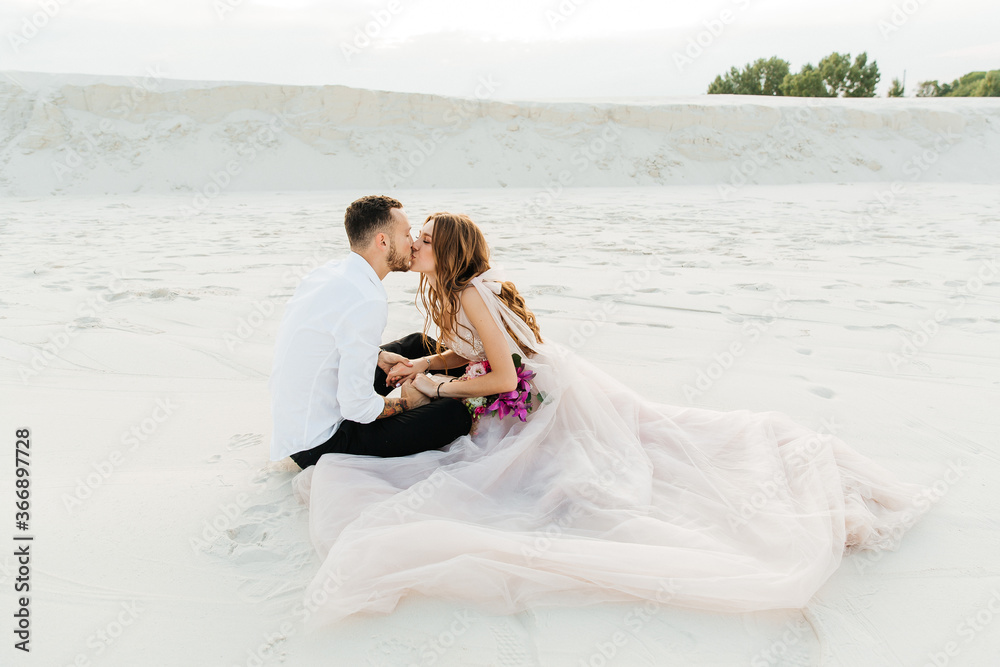 Love Story of a beautiful couple in a pink wedding luxury dress with a bouquet in the Sahara desert, sand, dunes