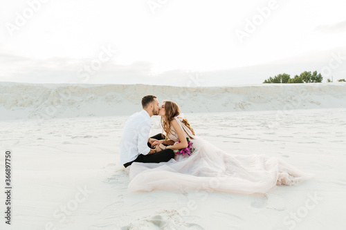 Love Story of a beautiful couple in a pink wedding luxury dress with a bouquet in the Sahara desert, sand, dunes