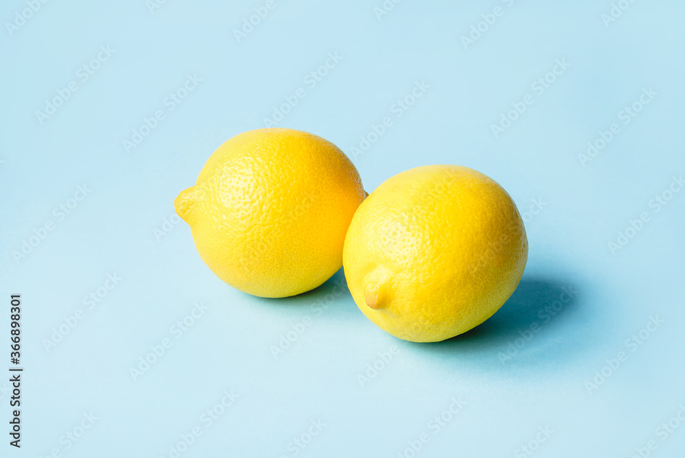 Two ripe lemons on a blue background. Minimal summer concept. Two ripe lemons on a blue background. Minimal summer concept.