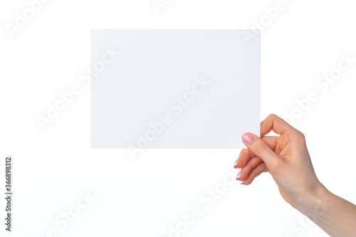 Female hand holding blank white sheet of paper isolated on white