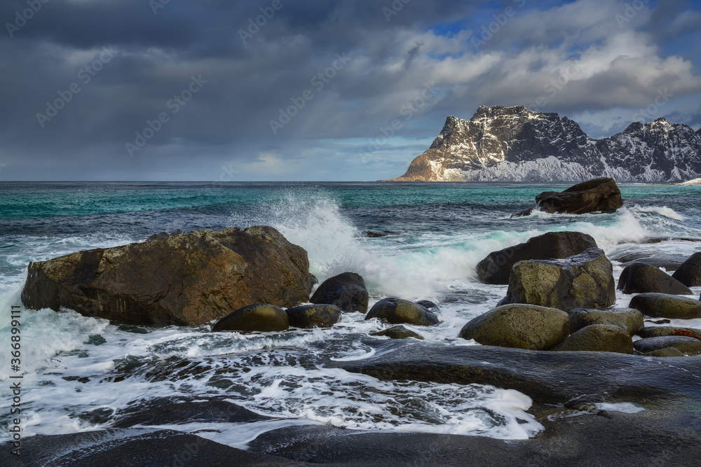 A wave breaks on the rocks on the rocky seashore