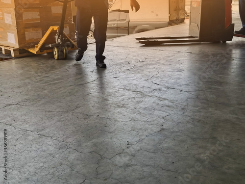 Worker driving forklift loading and unloading shipment carton boxes and goods on wooden pallet from container truck to warehouse cargo storage in logistics and transportation industrial 