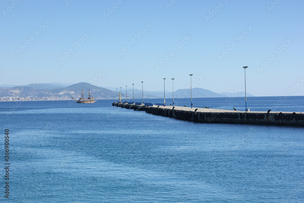 Alanya, TURKEY - August 10, 2013: Travel to Turkey. Rocks, wildlife of Turkey. Clear blue sky. The waves of the Mediterranean Sea. Water surface. Mountains and hills in the distance in the background.