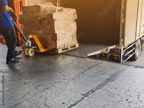 Worker driving forklift loading and unloading shipment carton boxes and goods on wooden pallet from container truck to warehouse cargo storage in logistics and transportation industrial  photo