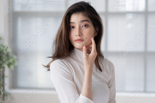 Asian woman is applying cream to her face.