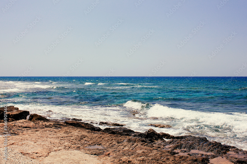 Background of blue sea. Rocky coast of the sea. Mediterranean sea in Cyprus. Nature background. Blue lagoon. Sea shore with summer Sunny day.