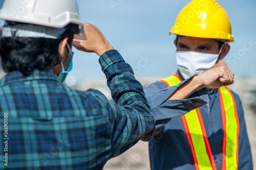 Asian man Engineer shake hand not touch new normal style,Two Engineer a wearing face mask protect corona virus PM2.5 on site construction