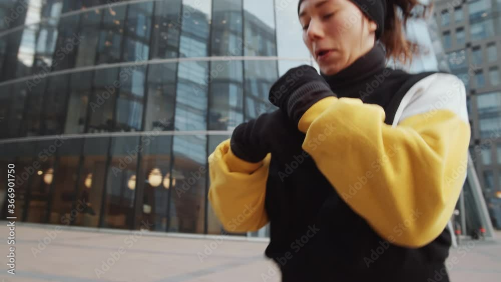 Tilt down shot of young Caucasian woman in sportswear doing warmup exercises before training outdoors in the city Tilt down shot of young Caucasian woman in sportswear doing warmup exercises before training outdoors in the city