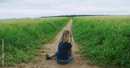 Little perschooler sittingin a field on a summer day photo