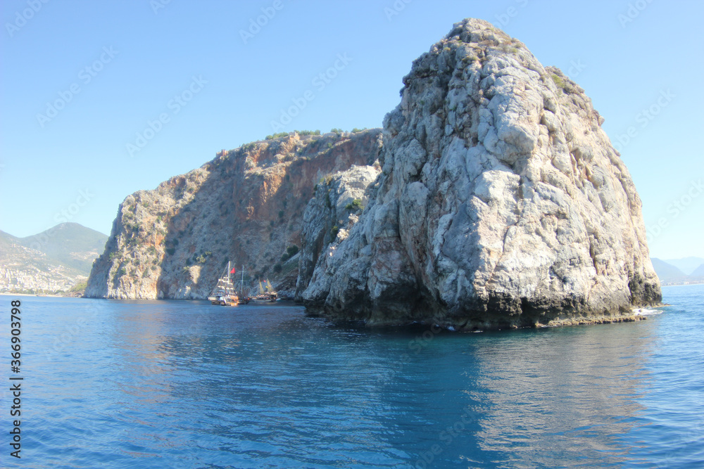 Fototapeta premium Alanya, TURKEY - August 10, 2013: Travel to Turkey. The waves of the Mediterranean Sea. Water surface. Mountains and hills on the coast of Turkey. Port. Green hills.