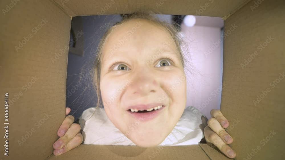 A little girl opens a cardboard box and shouts happily. Inside view of the box. Girl says wow