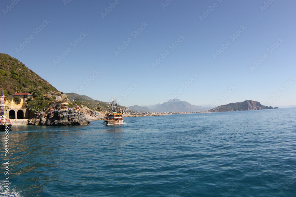 Alanya, TURKEY - August 10, 2013: Travel to Turkey. The waves of the Mediterranean Sea. Water surface. Mountains and hills on the coast of Turkey. Green hills.