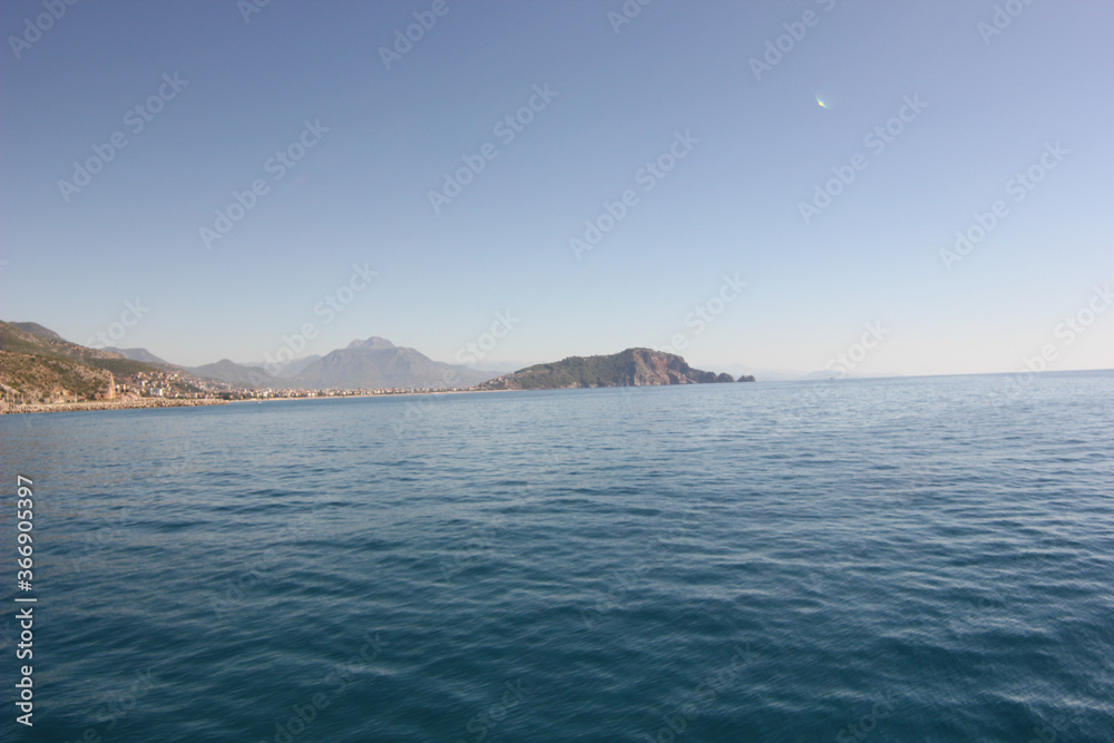 Alanya, TURKEY - August 10, 2013: Travel to Turkey. The waves of the Mediterranean Sea. Water surface. Mountains and hills on the coast of Turkey. Green hills.