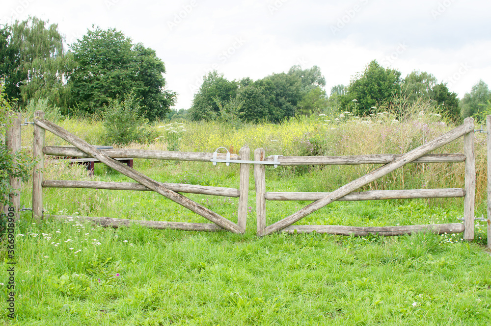 Old wooden closed gate that gives access to a meadow