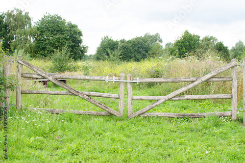 Old wooden closed gate that gives access to a meadow