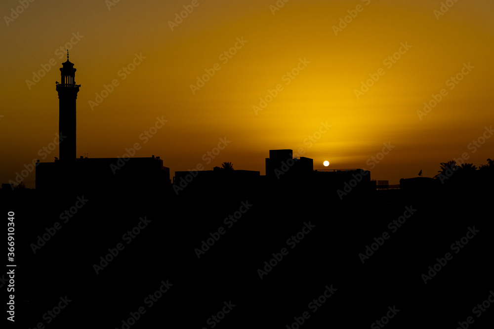 Sunset in the desert with a mosque in the forground asa silhouette on the Arabian peninsula 