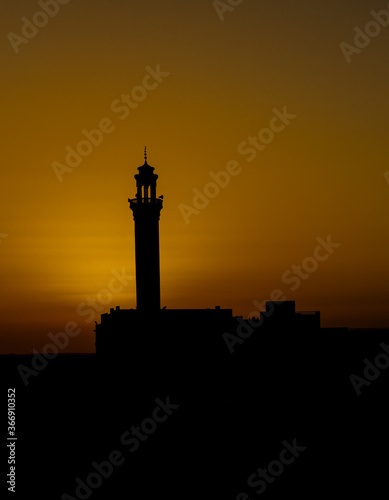 Sunset in the desert with a mosque in the forground asa silhouette on the Arabian peninsula 