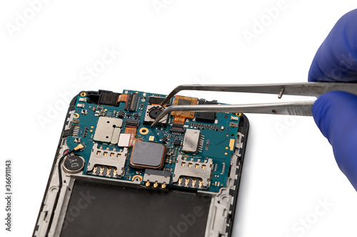 A technician repairs a smartphone camera module. Smartphone repair concept. Camera of the smartphone is taken with tweezers