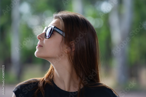 pretty girl with loose hair in sunglasses looks around.