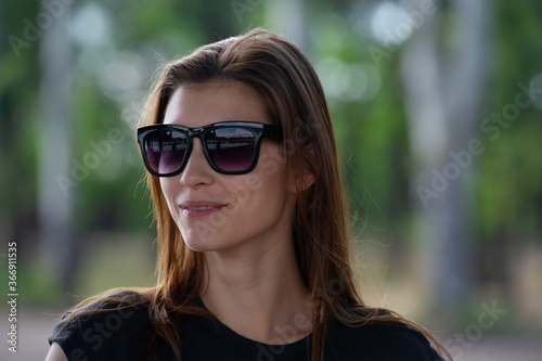 pretty girl with loose hair in sunglasses looks around.