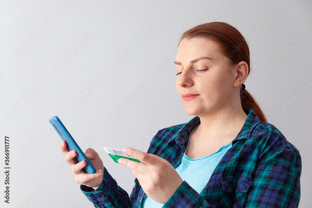 Beautiful young woman online shopping with credit card and smartphone sitting at home. Contactless payment concept Beautiful young woman online shopping with credit card and smartphone sitting at home. Contactless payment concept