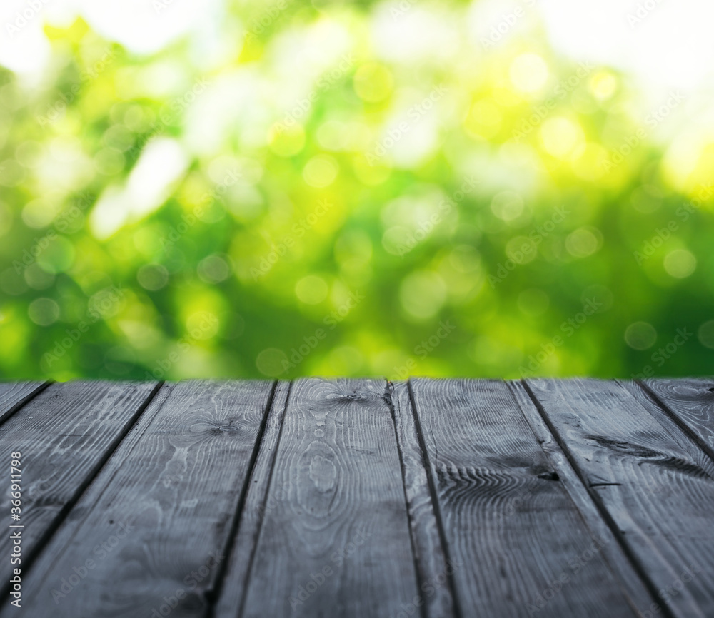 Empty wood table top on blur abstract green garden in the morning. Concept for montage product display or design layout Empty wood table top on blur abstract green garden in the morning. Concept for montage product display or design layout
