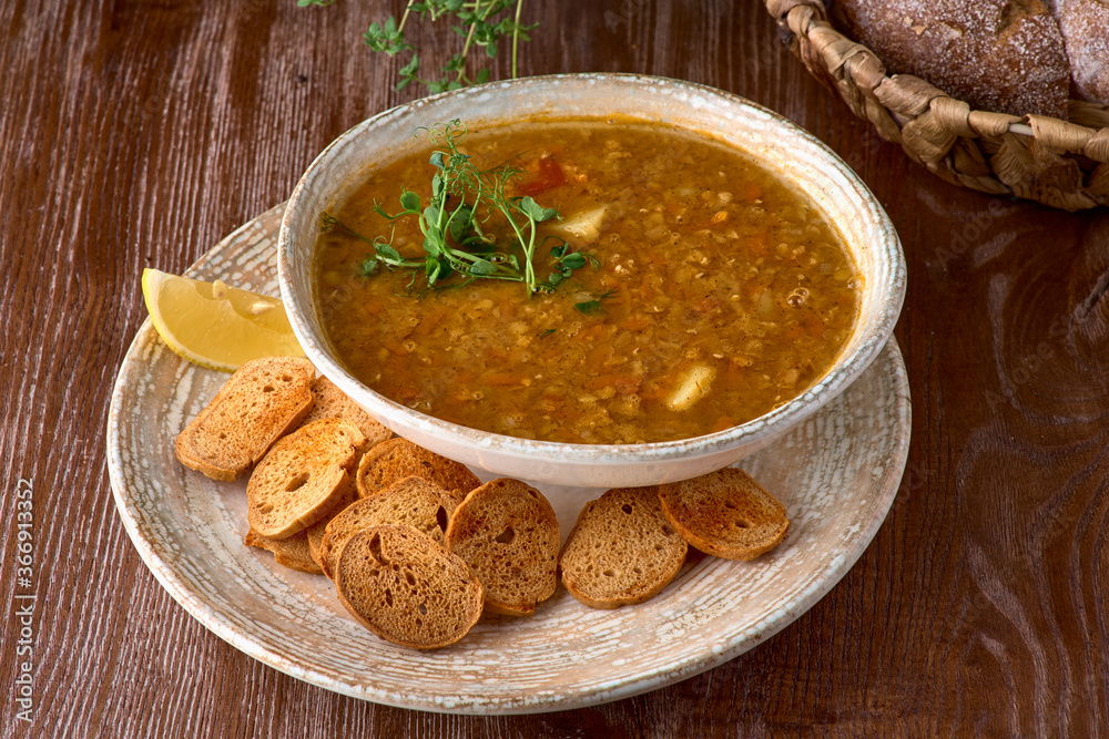 Lentil soup with smoked paprika and bread in a ceramic bowl on a wooden background Lentil soup with smoked paprika and bread in a ceramic bowl on a wooden background